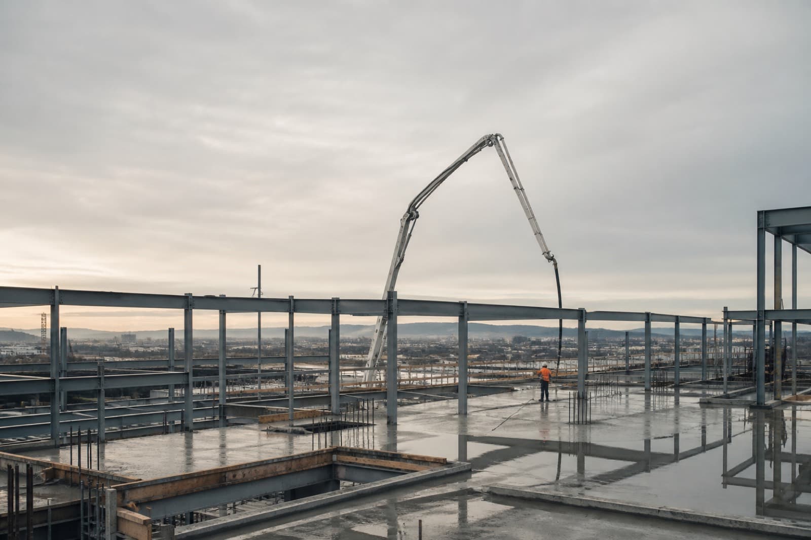 Early morning on a commercial jobsite: a concrete deck pour inside a structural steel frame.